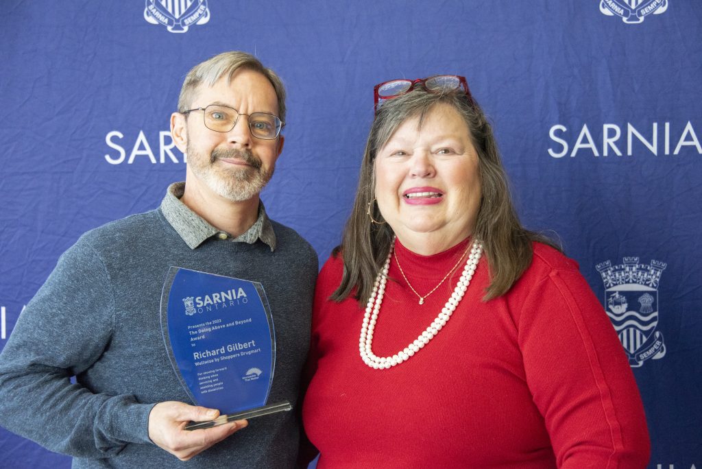 Two individuals, one holding an award.