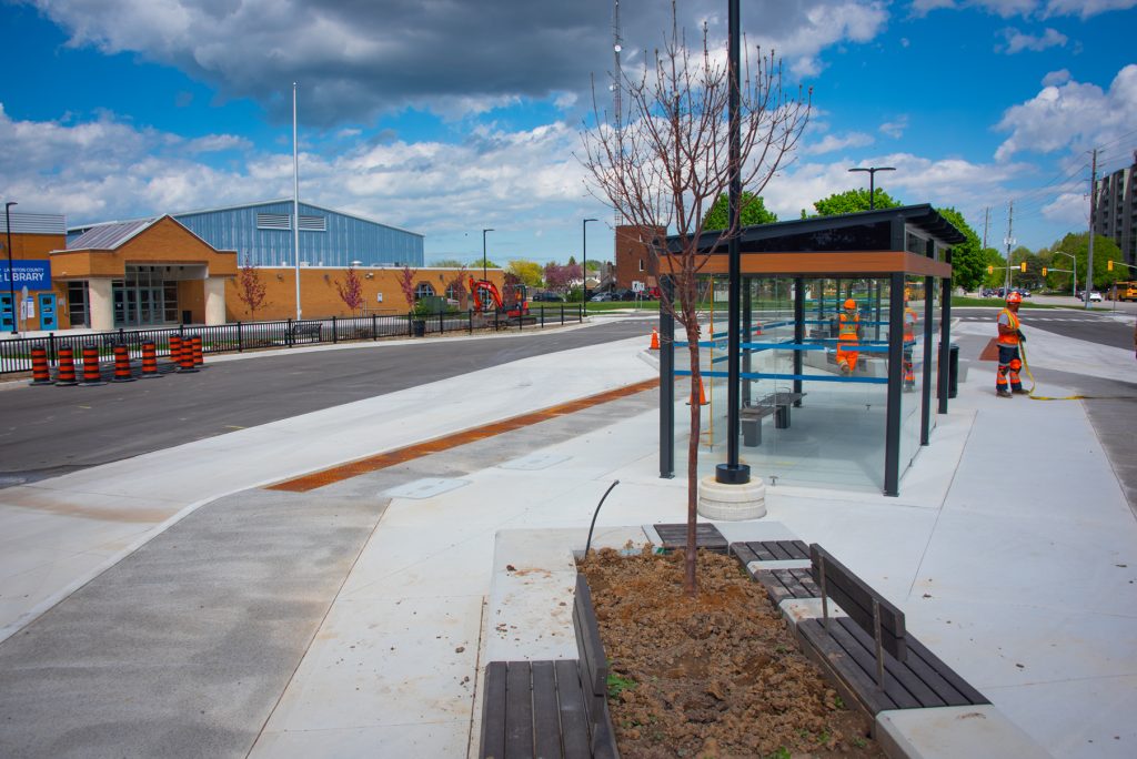 A concrete pad with bus shelters placed on it, alongside planters and benches.