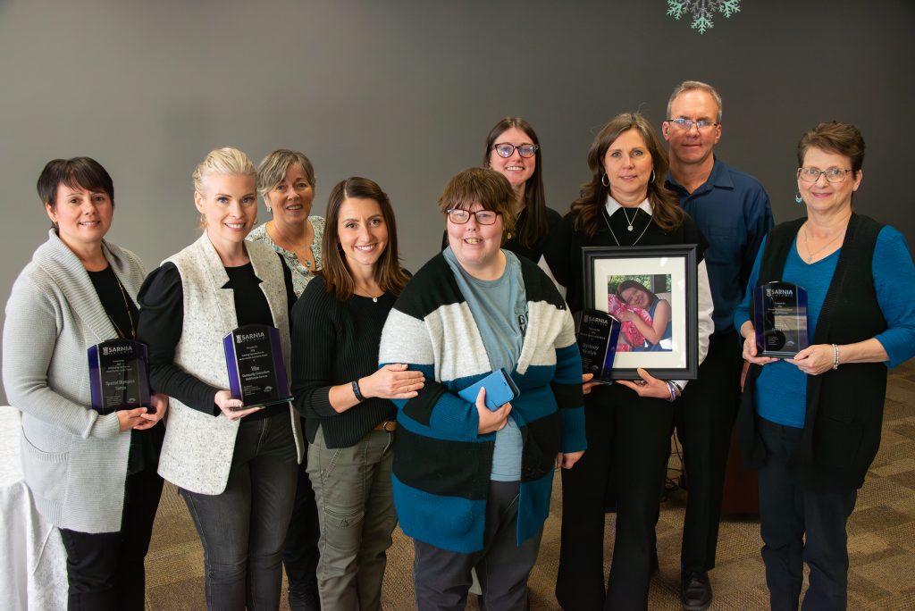 Photo of nine individuals holding award plaques.